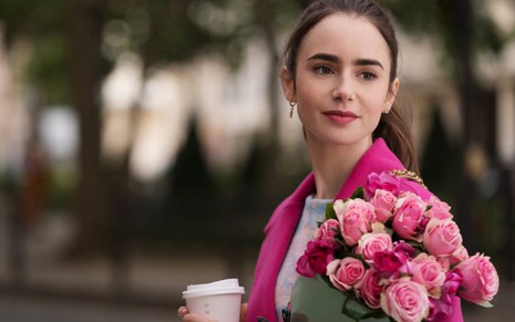 A atriz Lily Collins segura buquê de rosas e copo de café em cena de Emily em Paris, da Netflix