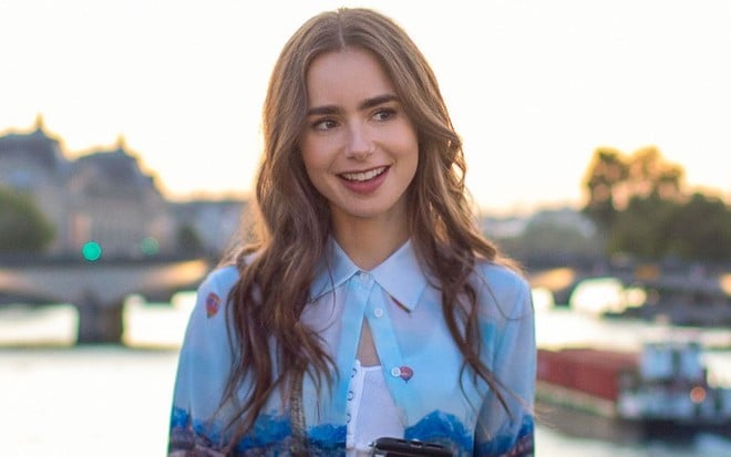 Com uma bela imagem de Paris ao fundo, Lily Collins sorri em cena da primeira temporada de Emily em Paris