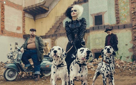 Emma Stone caracterizada como Cruella segurando três cachorros da raça Dálmata