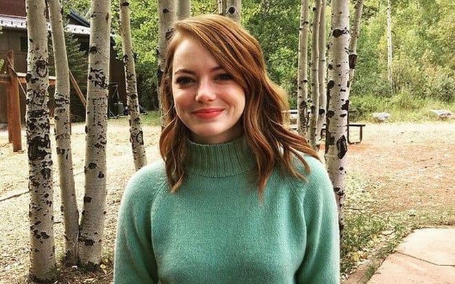 Emma Stone de cabelo ruivo e blusa de gola alta verde