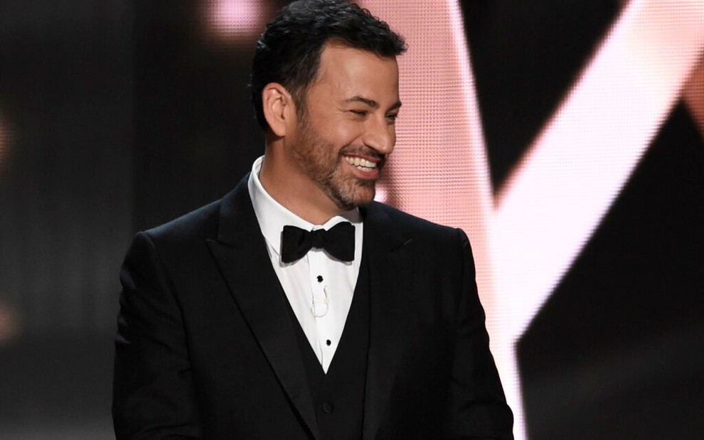 Jimmy Kimmel veste um smoking preto e branco na medida e abre um largo sorriso em cima do palco do Emmy de 2016