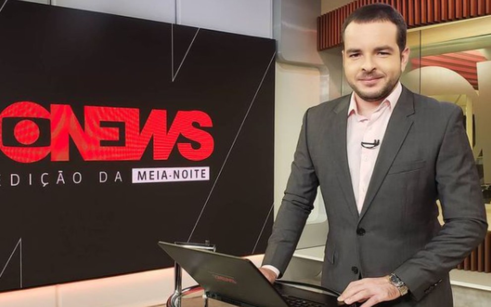 Erick Bang de blazer cinza, camisa branca, no estúdio da GloboNews