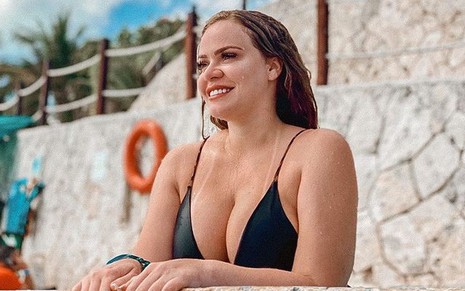 Paulinha Leite sorridente, de biquíni preto na piscina