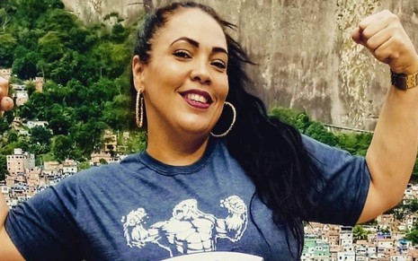 Imagem de Fabiana Escobar, a Bibi Perigosa, de braços abertos e camiseta azul