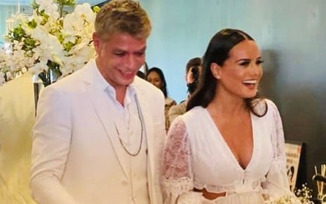 Fabio Assunção de terno e camisa brancos ao lado da noiva, Ana Verena, de vestido branco rendado e decotado
