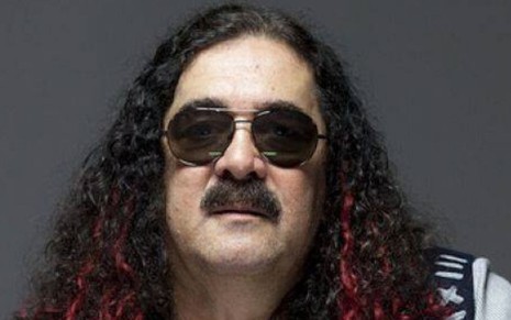 O cantor e compositor Moraes Moreira de óculos escuros, cabelo longo e bigode