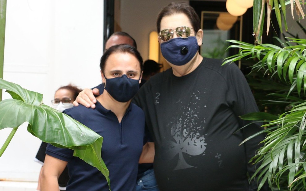Imagem de Felipe Massa e Fausto Silva abraçados e usando máscaras de proteção