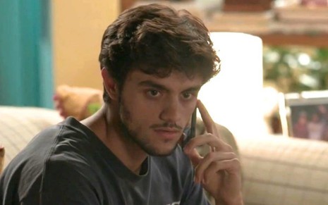 O ator Felipe Simas fala ao telefone e tem uma expressão séria em cena como Jonatas na novela Totalmente Demais