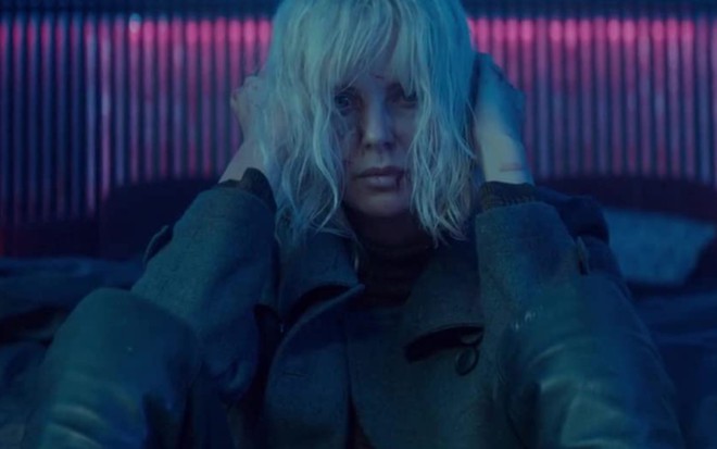 Charlize Theron com as mãos apoiadas na cabeça, com uma feição de preocupada