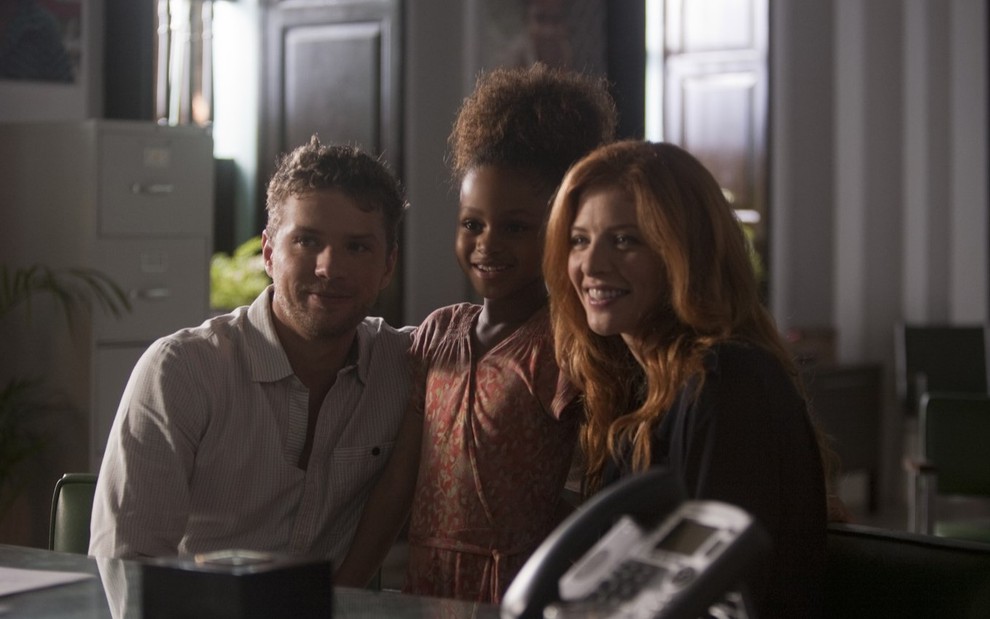 Steven (Ryan Phillippe) e Shannon (Rachelle Lefevre) sorriem e abraçam Nina (Briana Roy) que está em pé entre eles