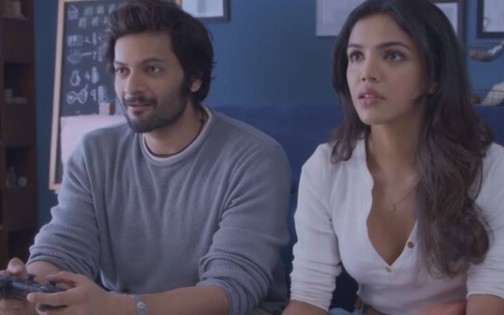 Em cena do filme Preso em Casa, da Netflix, os atores Ali Fazal e Shriya Pilgaonkar jogam vídeo-game