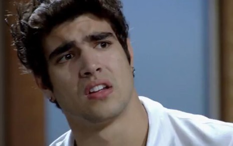 Caio Castro faz cara de abobalhado em cena de Fina Estampa em que usa uma camisa branca e está com a cabeça entrortada