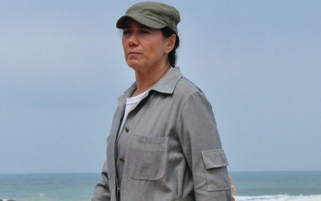 Lilia Cabral numa praia, com macacão de operária, caracterizada como Griselda na novela Fina Estampa