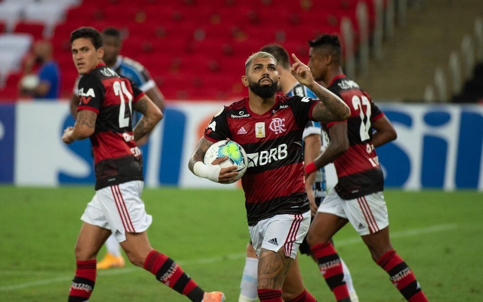 Com a bola na mão, Gabigol olha para cima e comemora gol do Flamengo; outros jogadores estão ao lado dele