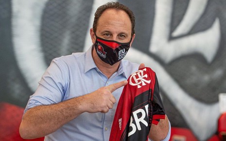 Imagem de Rogério Ceni, de máscara, segurando a camisa do Flamengo