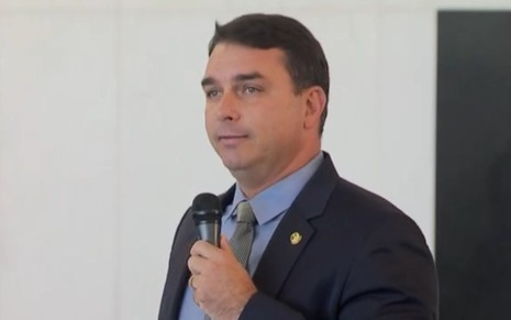 O senador Flávio Bolsonaro segura o microfone enquanto discursa