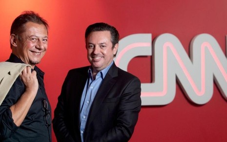 Os executivos Flavio Ferrari e Marcus Chisco, vice-presidente da CNN Brasil, posam em frente ao logo da CNN Brasil na parede