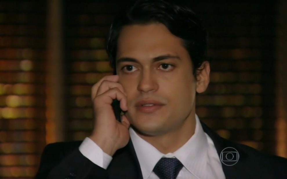 O ator Raphael Vianna em cena como Hélio de Flor do Caribe, falando ao celular