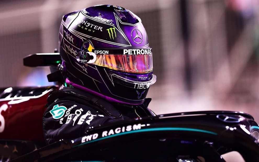 Com capacete, o campeão Lewis Hamilton pilota carro na Fórmula 1