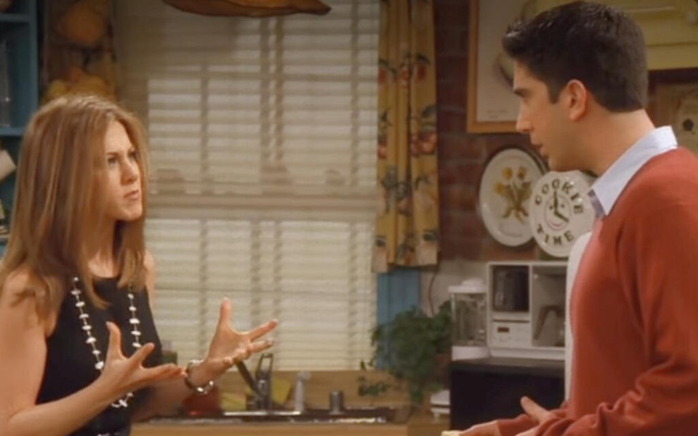 Dentro de uma cozinha estilosa, Jennifer Aniston grita contra David Schwimmer em cena da comédia Friends