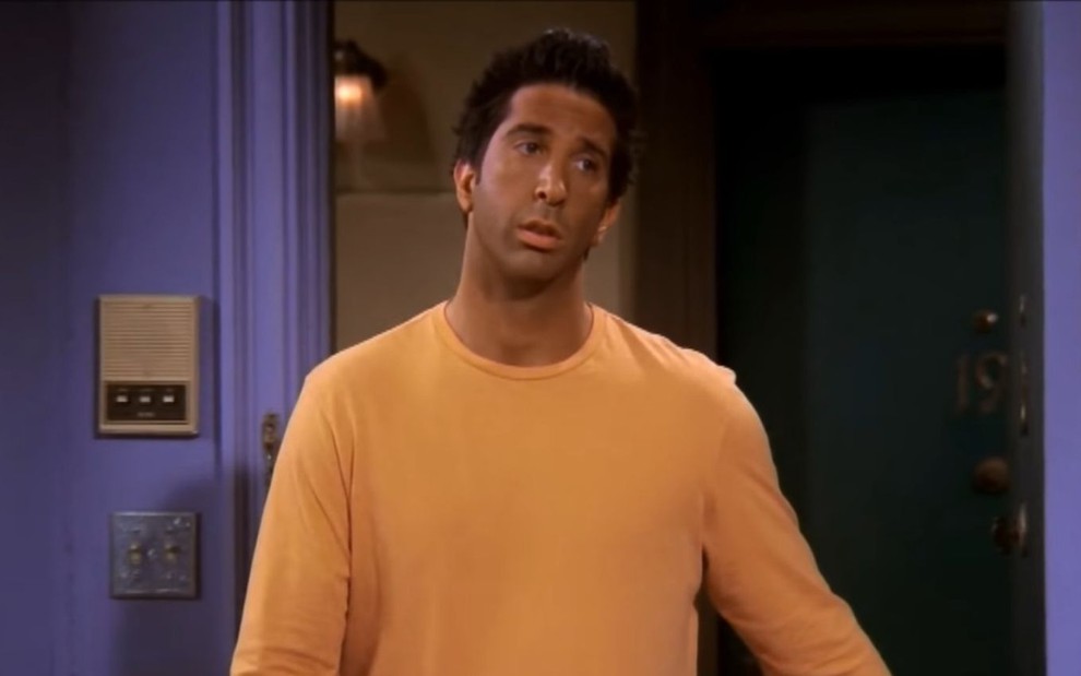 David Schwimmer de camisa amarela e expressão decepcionada interpretando Ross em Friends