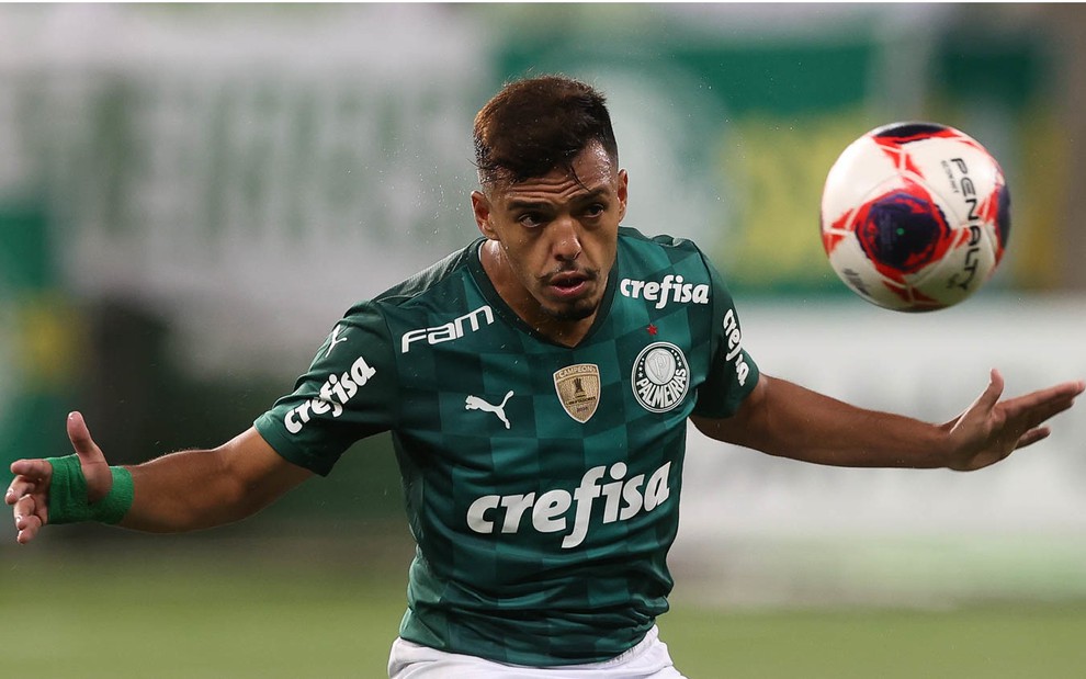 Jogador Gabriel Menino vestido com primeiro uniforme do Palmeiras (verde) com braços abertos durante jogada e olhando para a bola