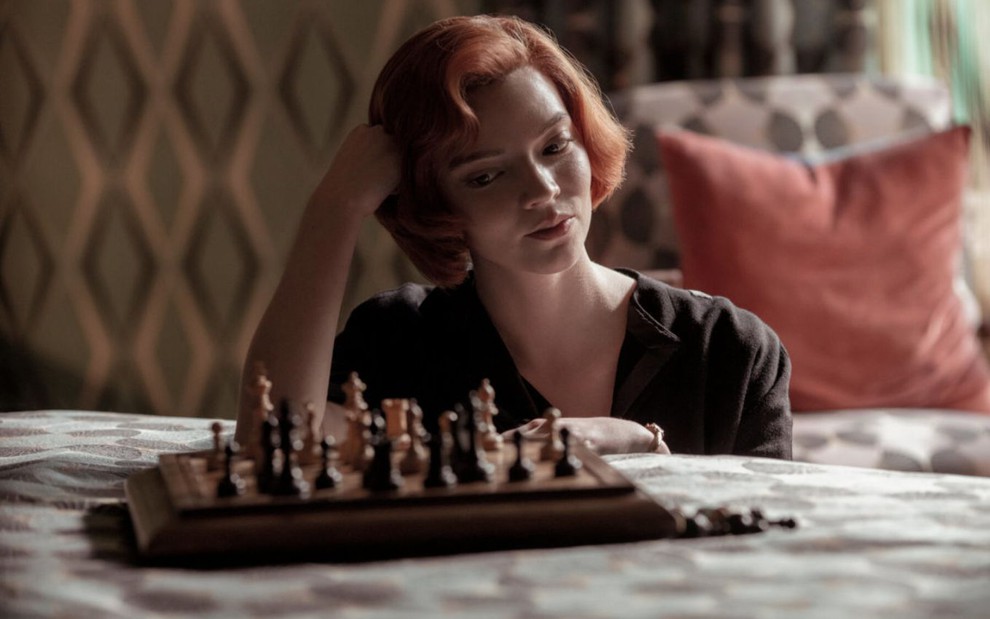 Anya Taylor-Joy olha para o lado com mão no cabelo em cena de jogo de xadrez como a protagonista Beth de O Gambito da Rainha