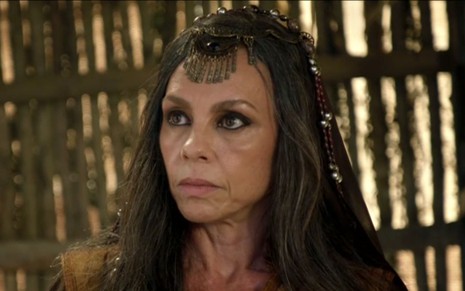 Carla Marins interpreta Adália em cena Gênesis: atriz olha com seriedade para alguém fora do quadro
