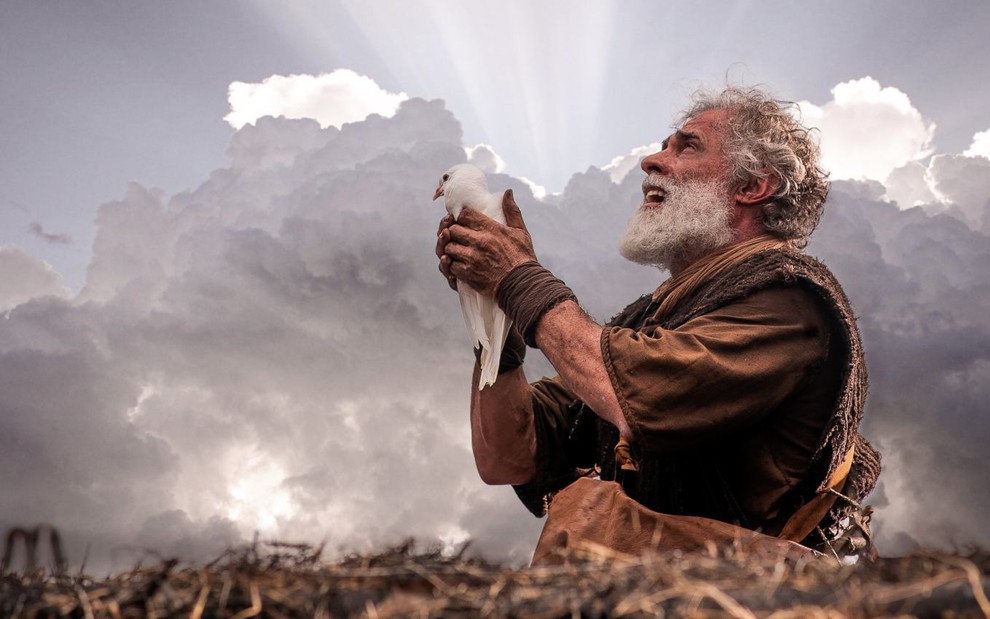O ator Oscar Magrini caracterizado como Noé, com uma pomba nas mãos, em cena de Gênesis