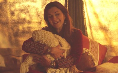 Adriana Garambone em cena de Gênesis: caracterizada como Sarai, atriz segura bebê no colo