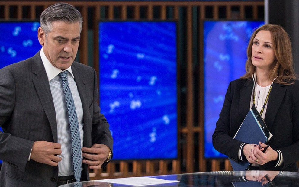 Em um estúdio de TV, George Clooney conversa com Julia Roberts em cena do filme Jogo do Dinheiro (2016)