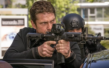 Gerard Butler aponta uma arma para a direita em cena do filme Invasão ao Serviço Secreto (2019)