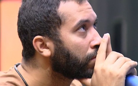Gilberto Nogueira, participante do BBB21, olha para a frente com ar preocupado enquanto põe as mãos no rosto