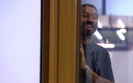 Gilberto Nogueira rindo, encostado na entrada do quarto do líder enquanto tenta ver Rodolffo pelado no banho