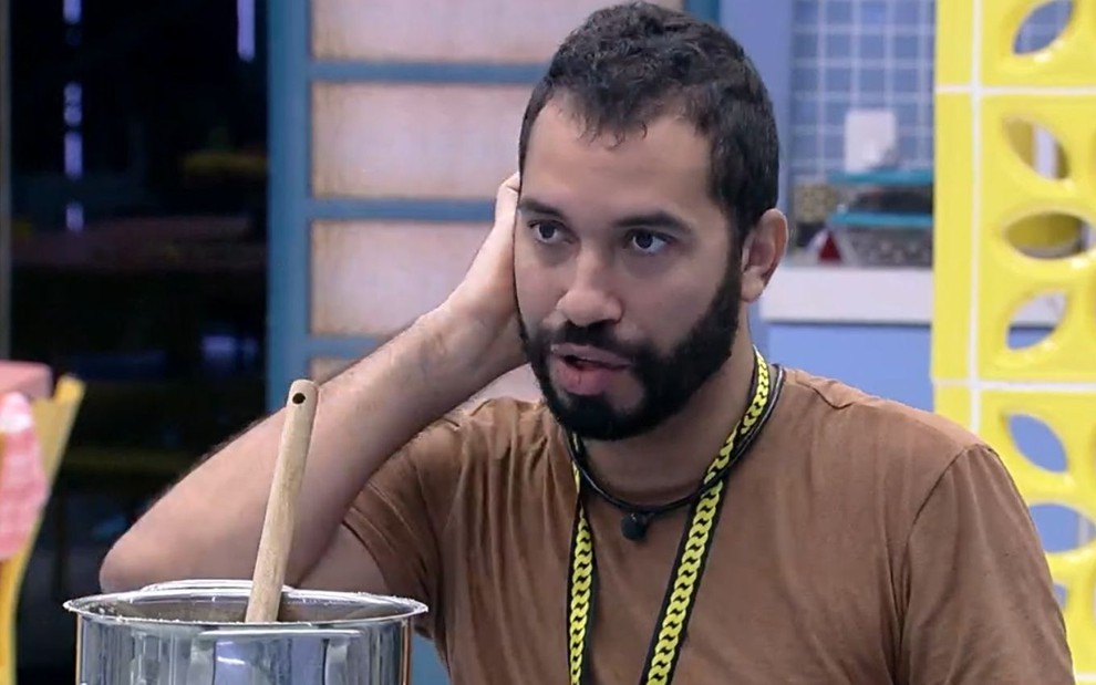 Gilberto Nogueira coça a nuca na cozinha do BBB21