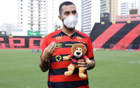 Gilberto Nogueiro usa a camisa do Sport em foto tirada no gramado da Ilha do Retiro, segurando leão, mascote do clube, de pelúcia