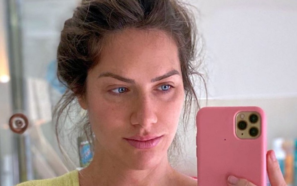 Com os cabelos presos em um coque e sem maquiagem, Giovanna Ewbank tira foto em frente ao espelho