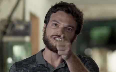 Emilio Dantas caracterizado como Rubinho em A Força do Querer: personagem encara alguém de fora do quadro e apontada o dedo em riste
