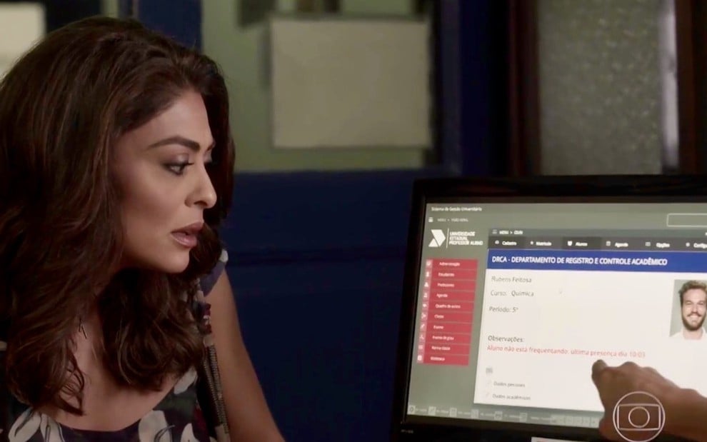 A atriz Juliana Paes olha para uma tela de computador assustada durante gravação da novela A Força do Querer