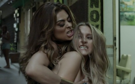 As atrizes Juliana Paes e Carla Diaz em cena de A Força do Querer: Juliana segura Carla pelos cabelos e faz cara de ódio para a parceira de cena