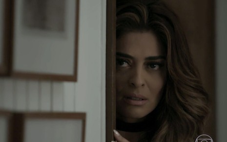 Juliana Paes caracterizada como Bibi em A Força do Querer: personagem está apoiada em uma porta, e olha com cautela para algo fora do quadro