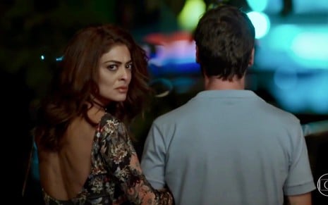 Juliana Paes olha para trás com expressão de raiva enquanto caminha abraçada com Emilio Dantas em cena de A Força do Querer