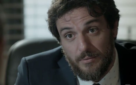 O ator Rodrigo Lombardi, com expressão de alerta, como Caio em A Força do Querer