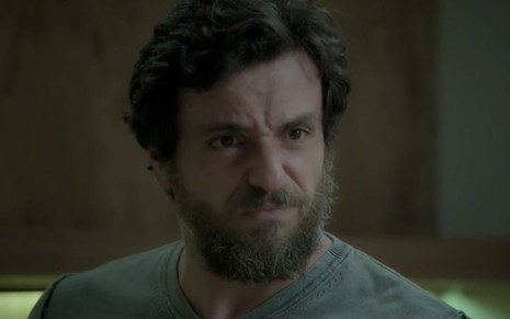 Rodrigo Lombardi caracterizado como Caio em A Força do Querer; ator olha de maneira séria para alguém fora do quadro