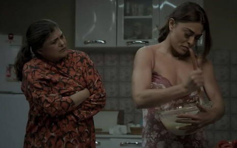De braços cruzados, Elizângela como Aurora observada Juliana Paes bater um bolo como uma tigela nos braços em A Força do Querer