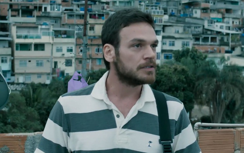 O ator Emilio Dantas usa camiseta com listras e olha para o lado em gravação de cena de A Força do Querer, da Globo