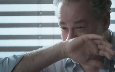 Dan Stulbach caracterizado como Eugênio em A Força do Querer: de camiseta branca, personagem coloca a mão no rosto e chora