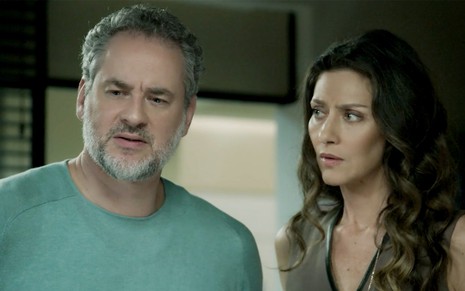 Dan Stulbach e Maria Fernanda Cândido em A Força do Querer: de camisa verde, ator olha desconfiado para alguém fora do quadro enquanto a atriz encara o parceiro de cena