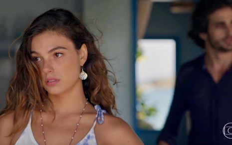 A atriz Isis Valverde com olhar perdido em cena da novela A Força do Querer como Ritinha, e ao fundo Fiuk aparece como Ruy