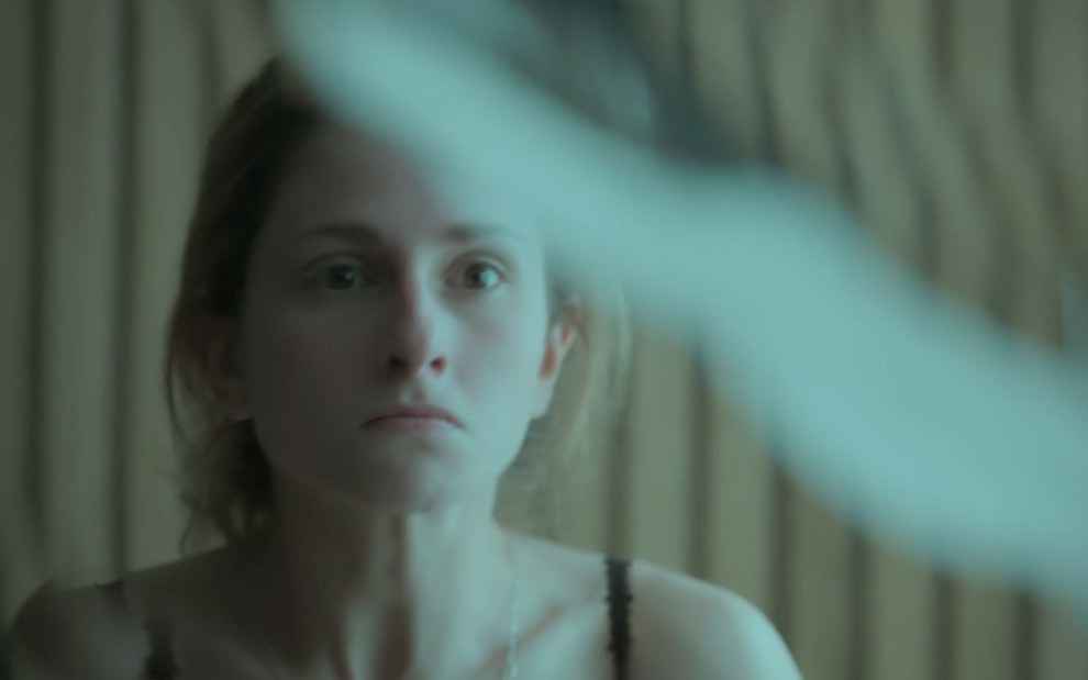 Close do rosto de Carol Duarte refletido em um espelho quebrado em cena de A Força do Querer